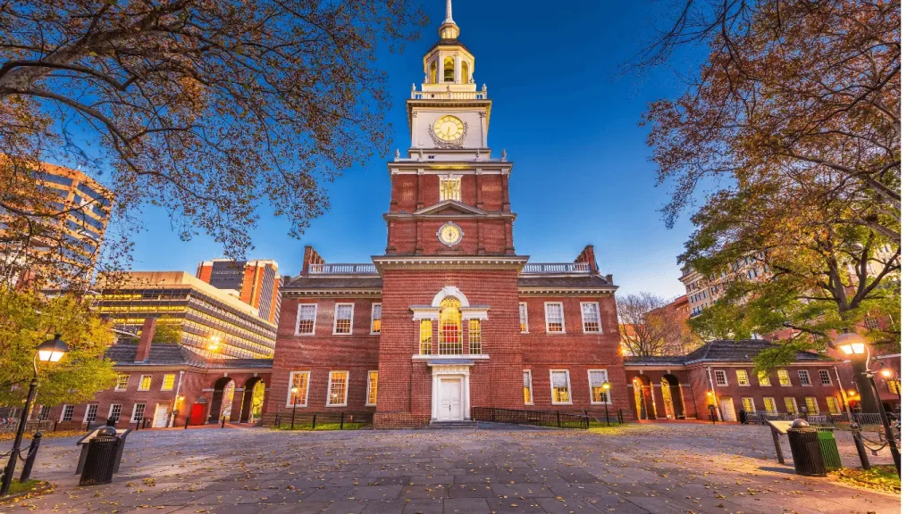 Independence Hall na Filadélfia ao entardecer, com céu limpo e árvores ao redor