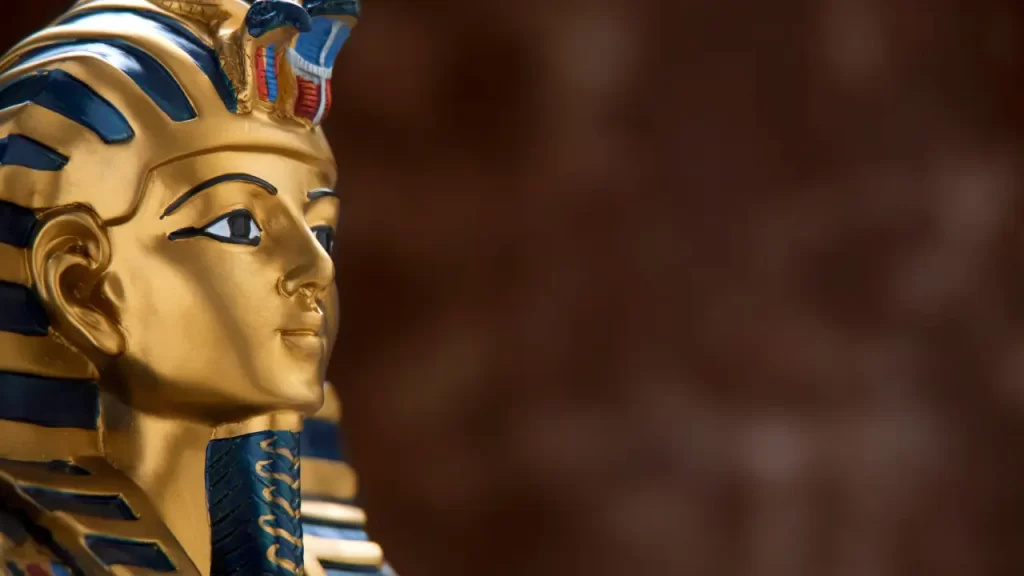 Máscara dourada de faraó egípcio com detalhes em azul, símbolo icônico da arte do Antigo Egito.